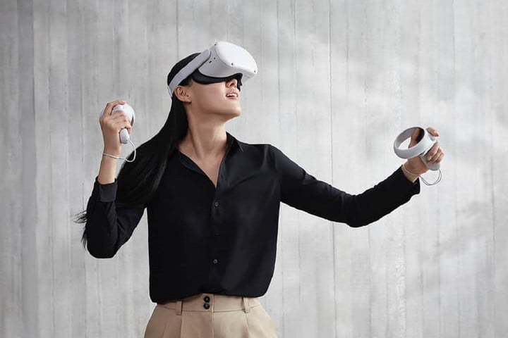 A woman using a virtual reality viewer after plugging in Oculus Quest 2 in front of a gray background. 