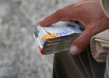 Geldwechsler hält Bündel Schekel in der Hand.