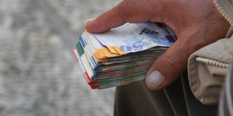 Geldwechsler hält Bündel Schekel in der Hand.